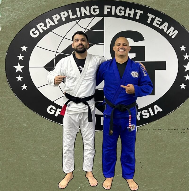 Shaheryar Khalid in a white gi and black belt, standing beside his professor