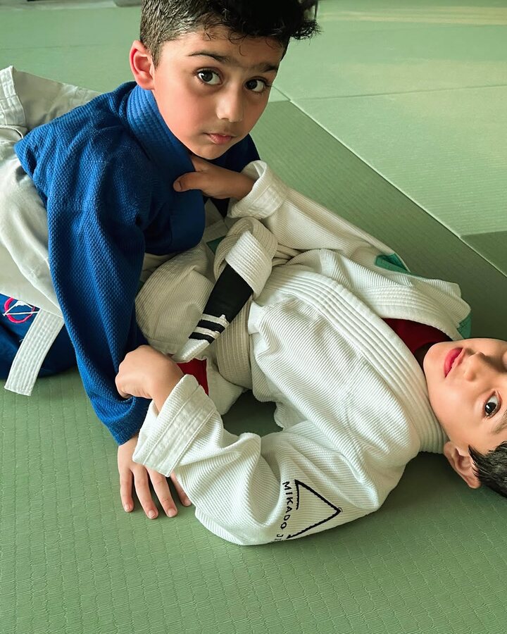 Two boys in gis practising a pin on the mats
