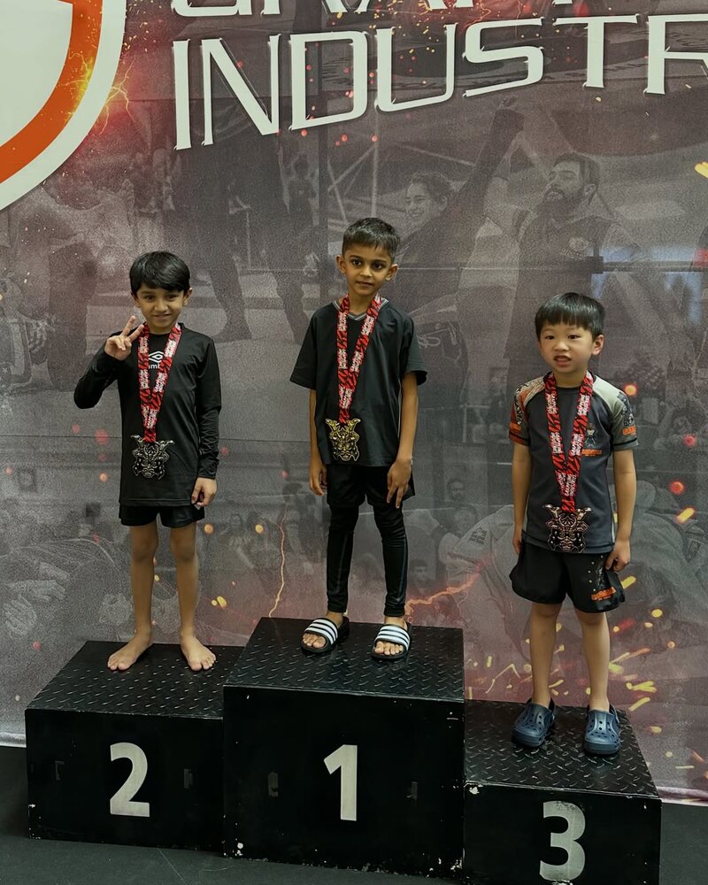 Three kids with their medals on the podium at Grappling Industries Kuala Lumpur