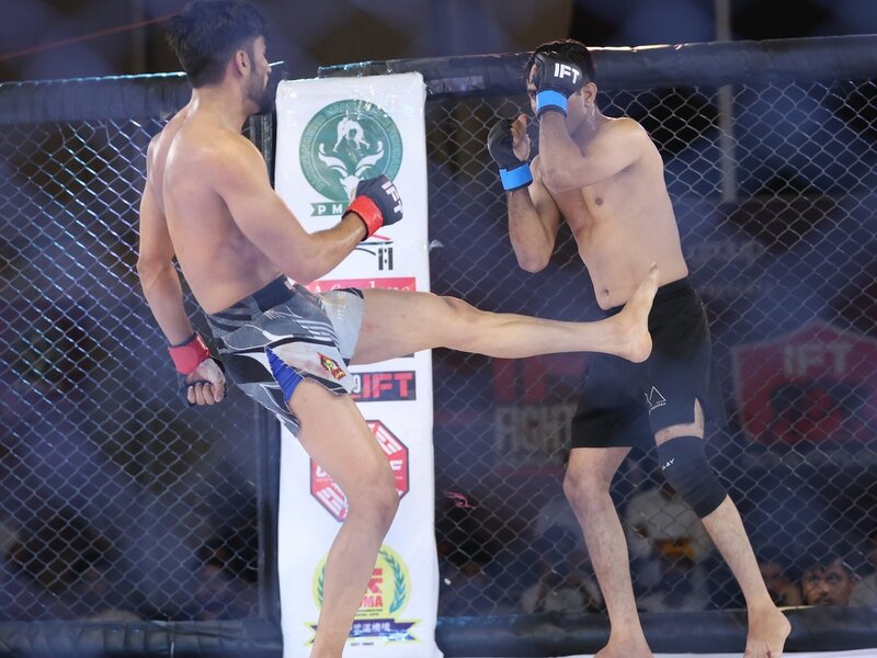 Coach Amjad Khan guarding against a kick in the cage at IFT Fight Pass Lahore
