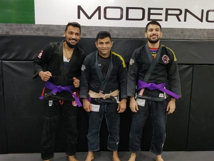 Shaheryar Khalid, right, in a black gi with his new purple belt, standing with his teammates