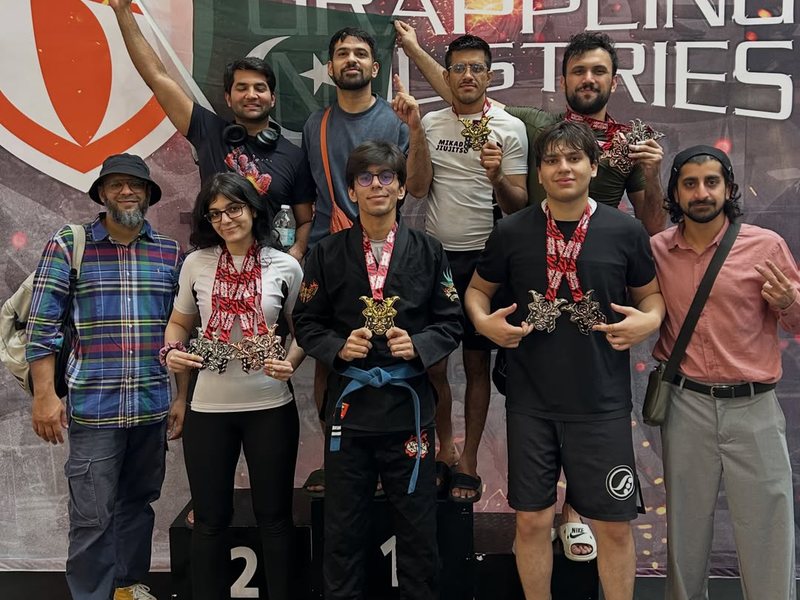 Team Mikado with their medals and the Pakistan flag in front of the Grappling Industries banner in Kuala Lumpur